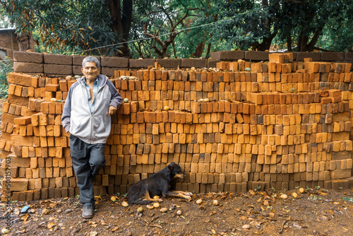 Elderly man lying on a pile of red bricks accompanied by his dog in a rural area of Rivas Nicaragua photo