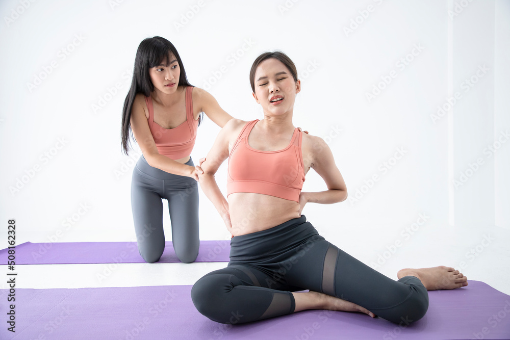 Pair of women accident and painful while doing yoga pose meditation in the white room. Healthy body posture with happy feeling in the morning. Sport and healthy concept. Pair of women accident and painful while doing yoga pose meditation in the white room. Healthy body posture with happy feeling in the morning. Sport and healthy concept.