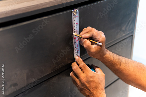 Carpenter's hands taking measurement to place drawer pulls