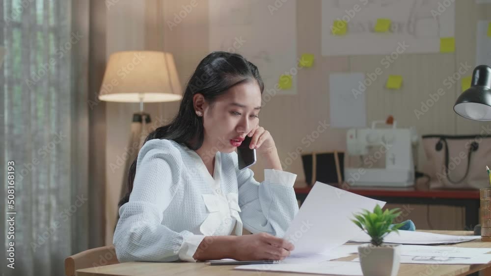Asian Woman Designer Talking On Smartphone While Looking At The Layout Bond In Hand At The Office
Asian Woman Designer Talking On Smartphone While Looking At The Layout Bond In Hand At The Office