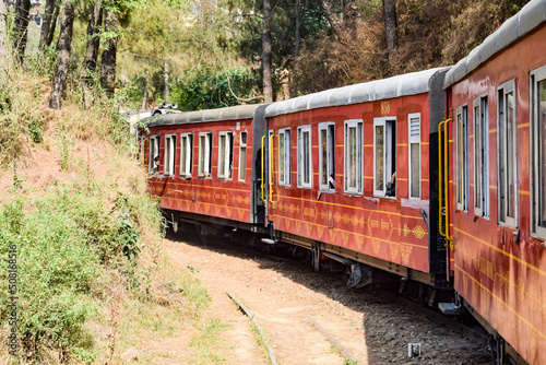 Toy Train moving on mountain slopes, beautiful view, one side mountain, one side valley moving on railway to the hill, among green natural forest. Toy train from Kalka to Shimla in India