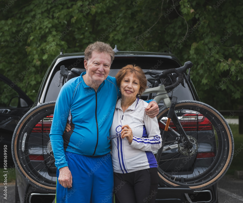Environmental portrait of senior couple bicyclists in front of there car with; bicycles behind them