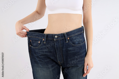 Concept of weight loss with thin girl on light background © Atlas