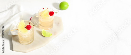 Glasses of tasty mai tai cocktail on light background with space for text