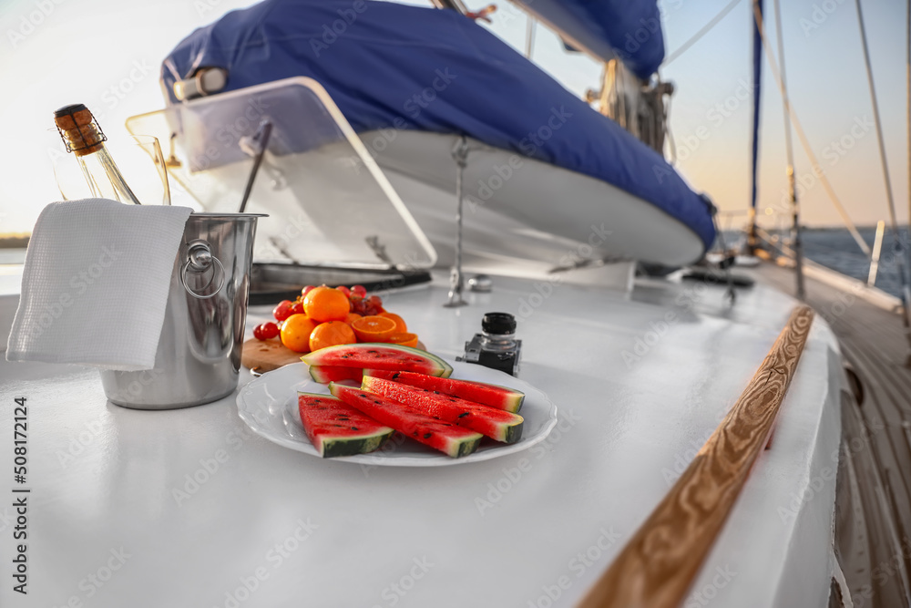 Fresh fruits with cold champagne and photo camera on deck of yacht - obrazy, fototapety, plakaty 
