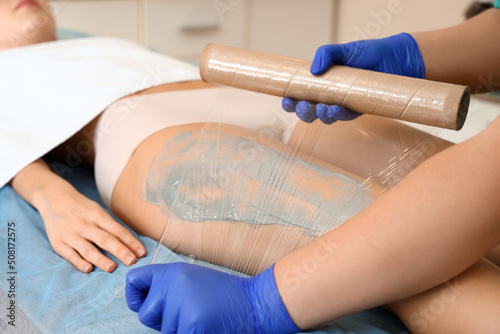 Young woman undergoing anti-cellulite wrapping in beauty salon © Pixel-Shot