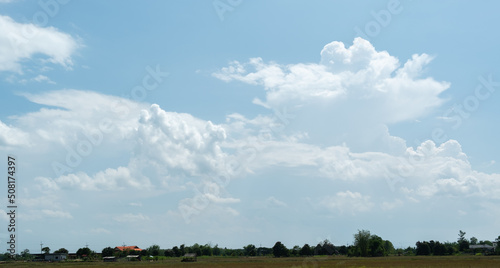 The white clouds have a quaint and rural shape. The sky is cloudy and blue