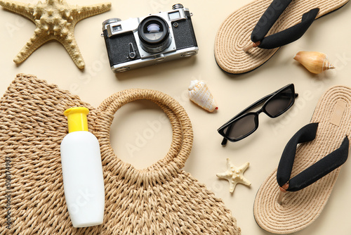 Sunscreen cream with photo camera and beach accessories on beige background