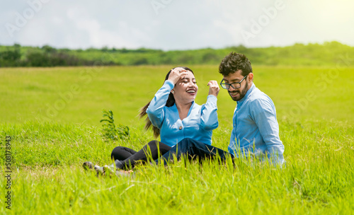 A couple in love sitting in the field, Romantic couple sitting on the grass outdoors, Smiling teenage couple sitting on the grass on a sunny day