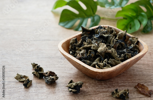 dried Chinese black fungus or mushroom in a wooden bowl on a wood background                             photo