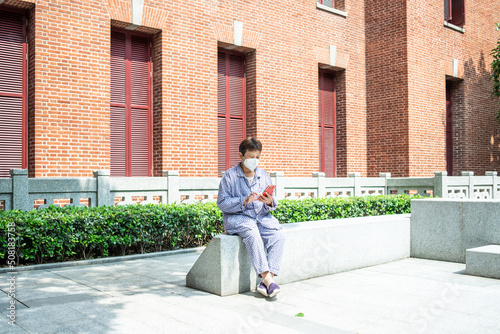 Hospitalized patient looking at mobile phone while basking in the sun
