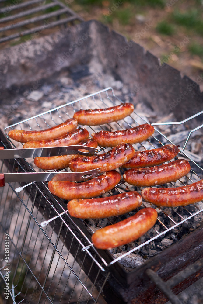 Tasty Sausages grilling on charcoal grill grate