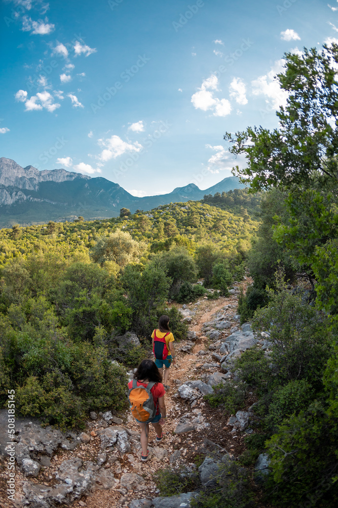 Two women with a backpack against the backdrop of a beautiful mountain and sky