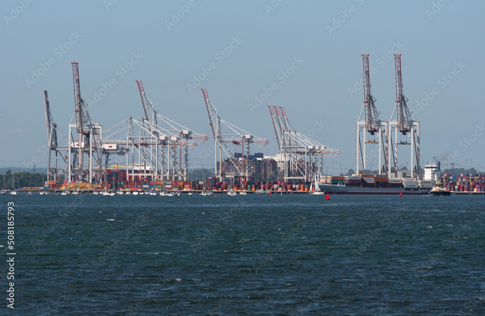 Southampton, England, UK. 2022. View of cranes and shipping at DP World container terminal and a small container ship the BF Fortaleza departing. Southampton Water, UK.
