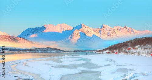 Panoramic view at fjord with coast of the Norwegian Sea, snowy mountains in the background Arctic Circle at sunset - Norway