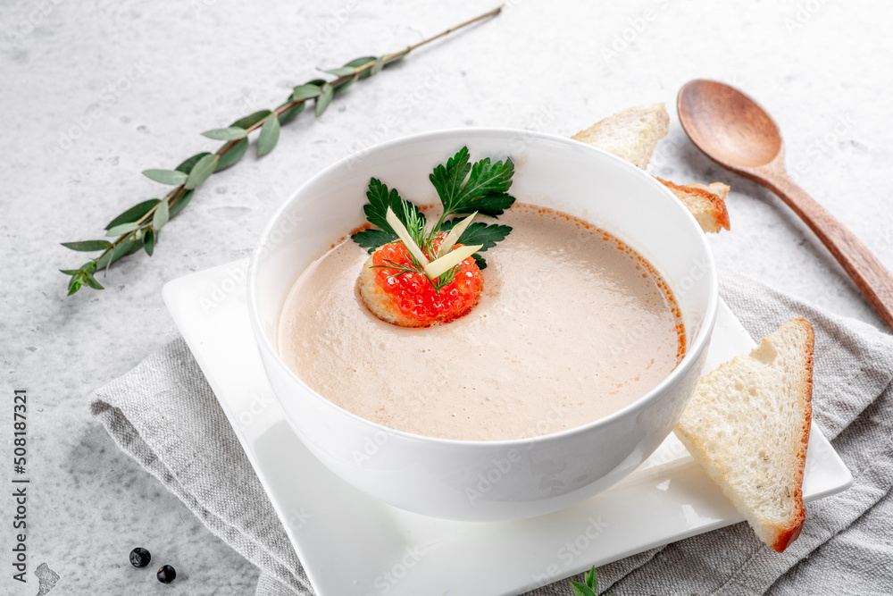 Fish cream soup with salmon in a white bowl decorated with crackers with red caviar Fish cream soup with salmon in a white bowl decorated with crackers with red caviar