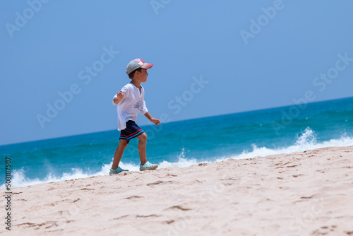 Obraz na płótnie Little boy walking on a tropical beach along the blue endless ocean w salonie