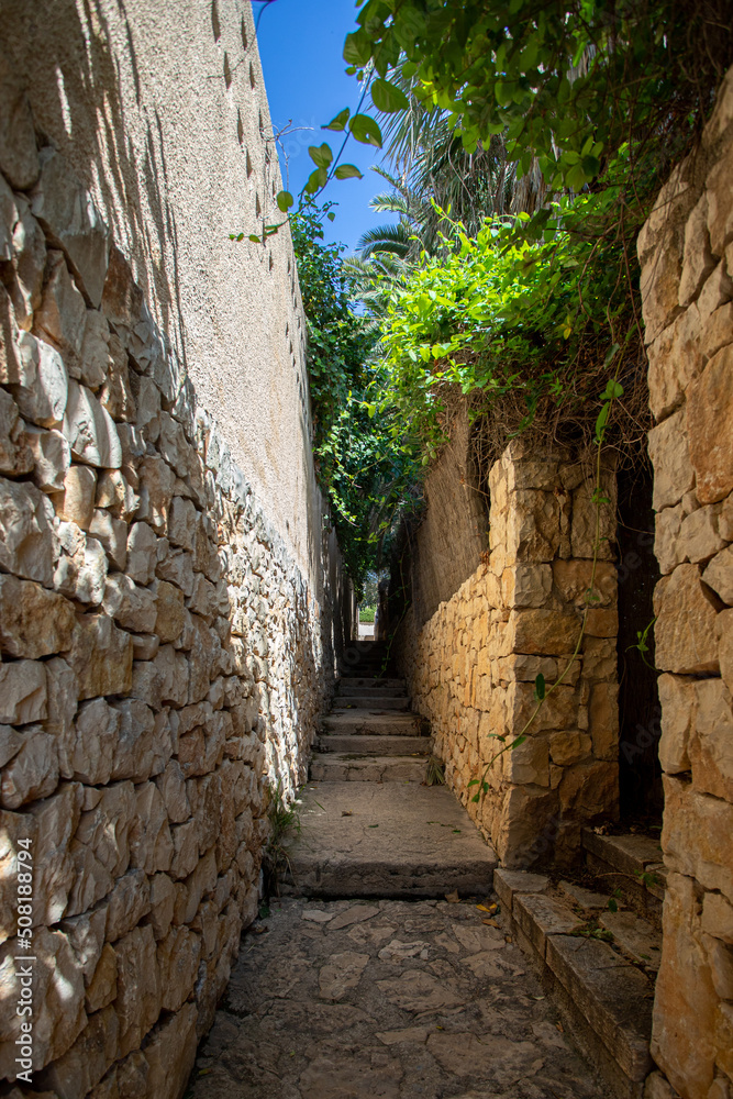 Exterior stone corridor with lots of shade and vegetation in summer.