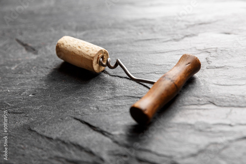 Vintage wine corkscrew in a cork on a black slate background. photo
