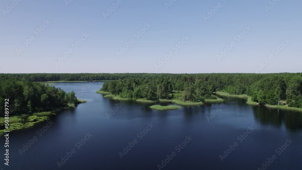 An azure lake surrounded by a dense forest and dotted with small islands. A green woods on the coast of a big pond. A clear sunny summer day in countryside scenery, a nice place to relax or fish. An azure lake surrounded by a dense forest and dotted with small islands. A green woods on the coast of a big pond. A clear sunny summer day in countryside scenery, a nice place to relax or fish.