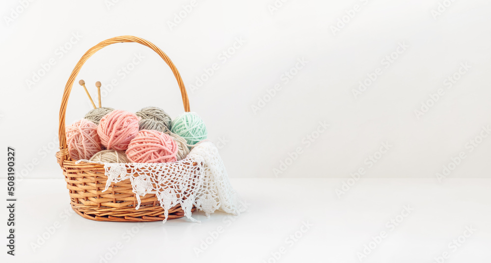Basket with balls of thread and knitting needles on a white background with copy space. Crochet, knitting as a hobby. Basket with balls of thread and knitting needles on a white background with copy space. Crochet, knitting as a hobby.