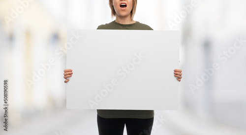 feminism and human rights concept - screaming woman with big white poster protesting on demonstration over city street background