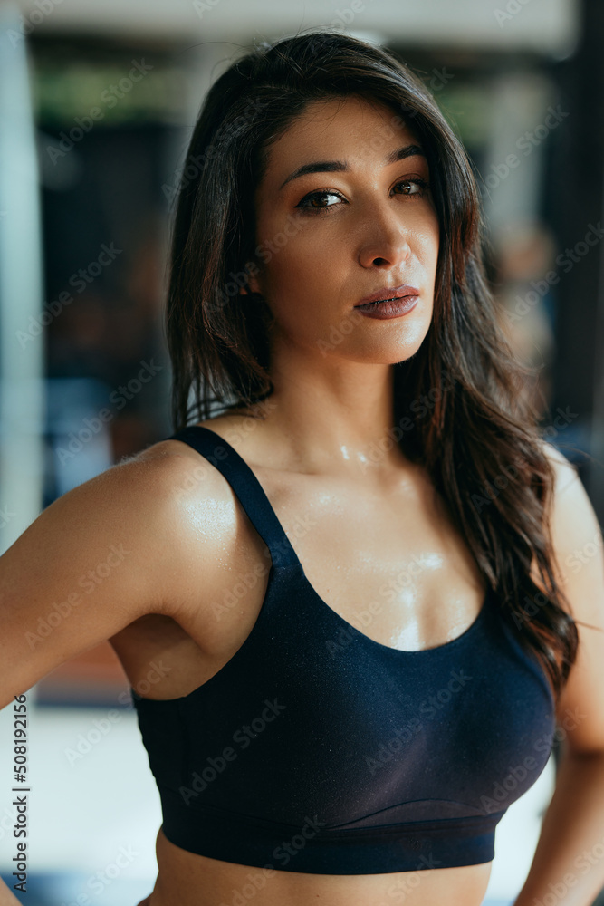 Portrait of a fit, muscular, sweaty sportswoman taking a break in a gym.