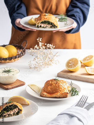 A chef serving Salmon en Croute on a white table