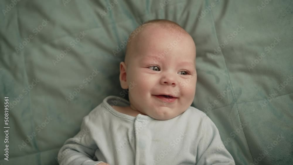 Portrait of a happy newborn baby on the background, top view. A little boy lies on the bed and laughs. Portrait of a happy newborn baby on the background, top view. A little boy lies on the bed and laughs.