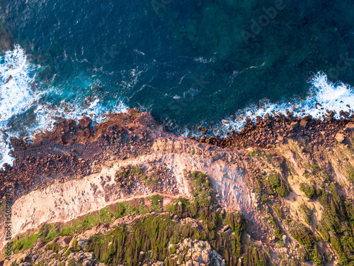 Waves' foam with sunset colors on the coast with mediterranean maquis