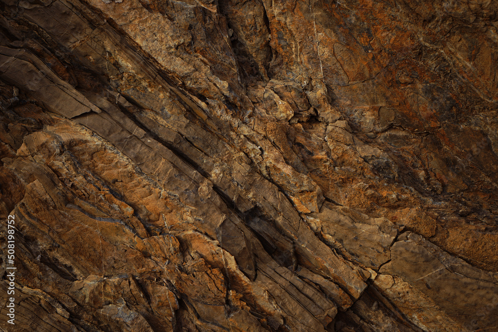 Brown rock texture with cracks. Rough mountain surface. Close-up. Stone background for design.