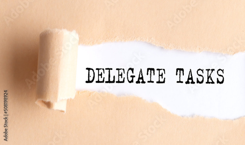 The text DELEGATE TASKS appears on torn paper on white background.