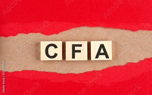 CFA word on wooden cubes on red torn paper , financial concept background