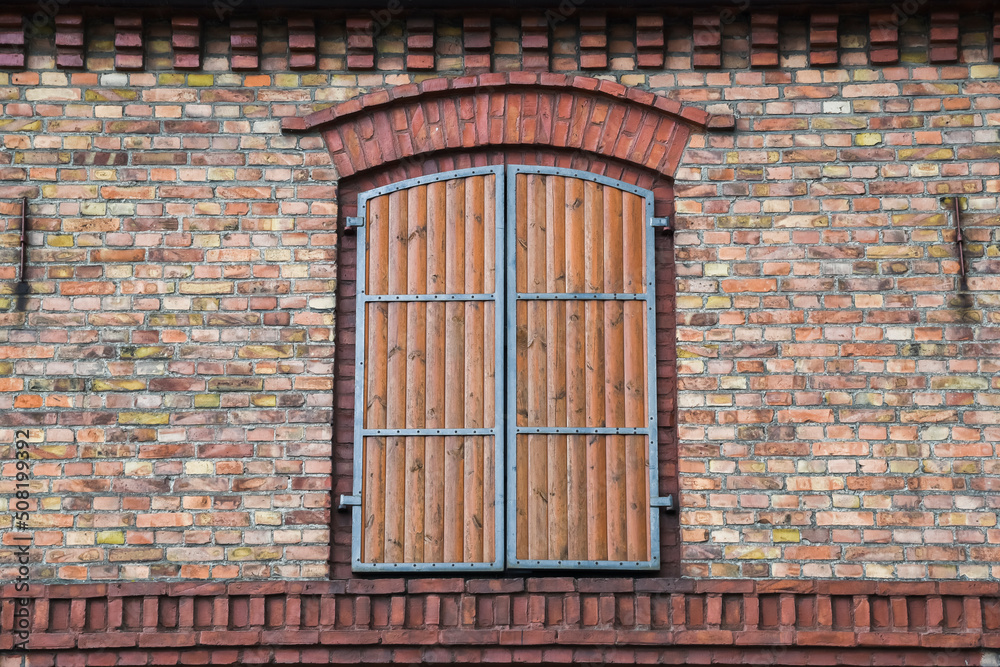 A wooden shutter in a red brick building.
