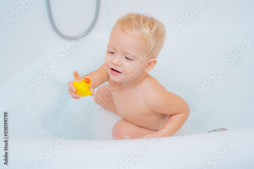 Kids playing in tub. Wash infant hygiene and health and skin care. Childs hygiene. Bath toy duck. Bubble bath.