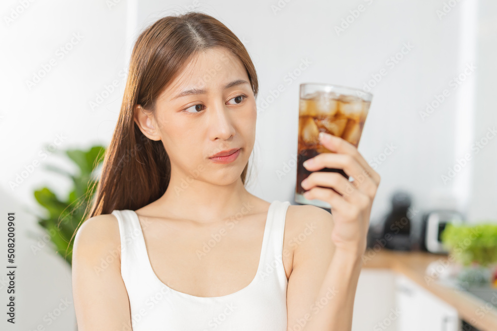 Avoid, limits sweet sugar, choose asian young woman, girl holding, looking at a glass of cold cola soft drink soda, sparkling water with ice by her hand. Health care, healthy diet lifestyle concept. Avoid, limits sweet sugar, choose asian young woman, girl holding, looking at a glass of cold cola soft drink soda, sparkling water with ice by her hand. Health care, healthy diet lifestyle concept.