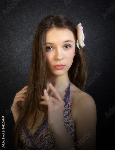 Portrait of a girl on a dark background with a flower in her hair.