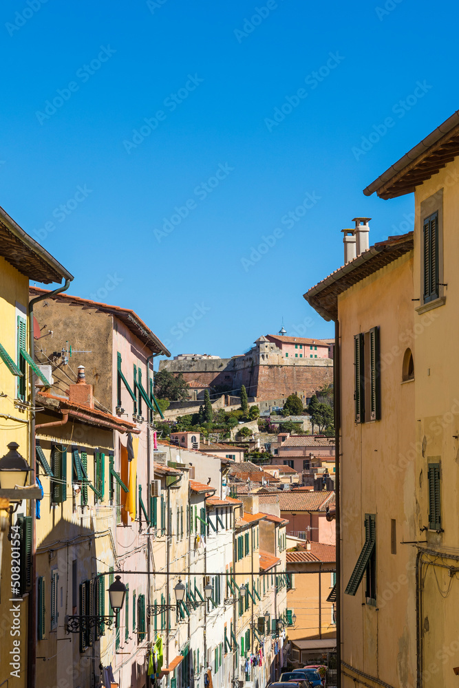 Street with typical Italian houses in the island capital Portoferraio on the island of Elba in Italy under a bright blue sky in summer