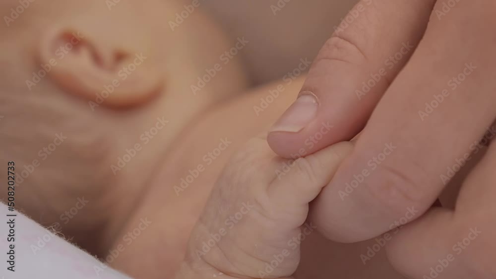 Mother touching Hand of sleeping baby with selective focus. Close up tiny fingers Mother touching Hand of sleeping baby with selective focus. Close up tiny fingers