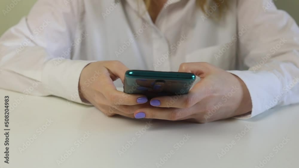 A girl sits with her phone at her desk and works. A girl sits with her phone at her desk and works.