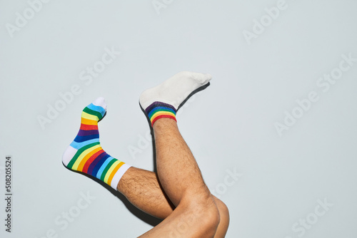 Fotografía Minimal shot of playful man wearing mismatched socks with rainbow symbols feet u
