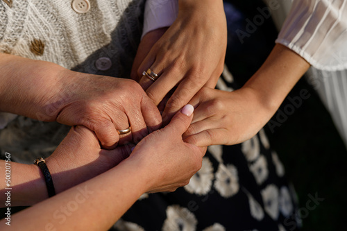 Hands of grandmother daughter and granddaughter on a background of sunlight 