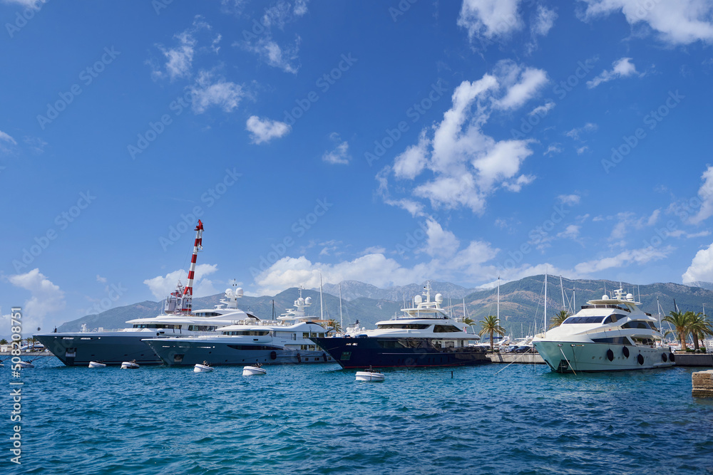 Moored luxury yachts against the backdrop of a mountains and blue sky