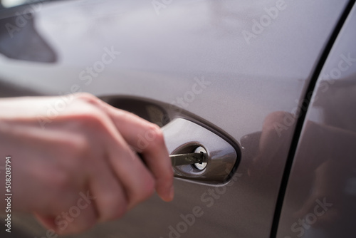 Close-up - the person opens the car door with a key of gray color