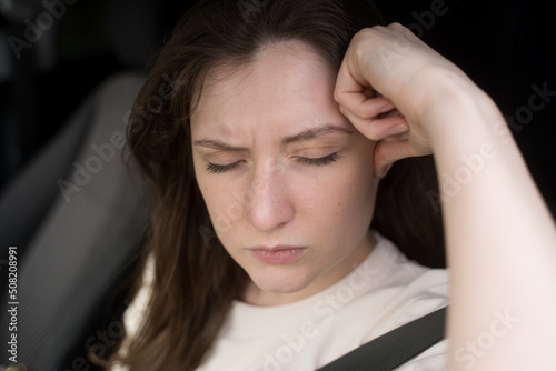 Headache in the car. The female driver is holding on to her head in pain. Stress behind the wheel of a vehicle