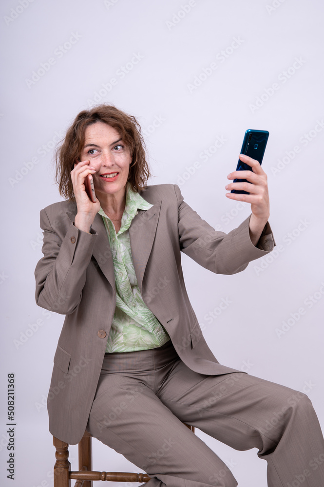 Frau im Anzug telefoniert lächelnd und hält ein zweites Handy hoch