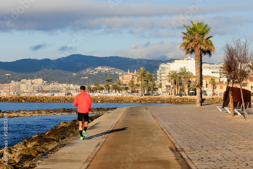Joven practicando running en un paseo marítimo de Palma de Mallorca (Islas Baleares, España), con la catedral al fondo. photo
