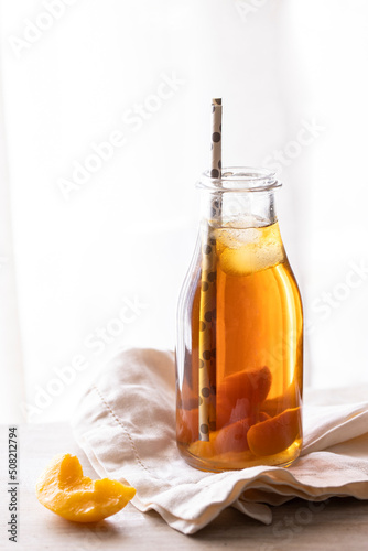 Homemade peach and lemon ice tea with mint on rustic background