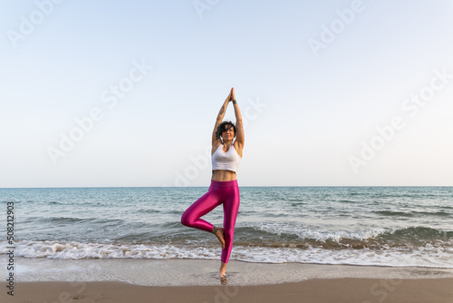 Butera, Italy – 26.06.2021: Woman Doing an Outdoor Lotus Yoga Position - Young healthy woman practicing yoga on the beach at sunset - Young Female wearing sport clothes in lotus 
