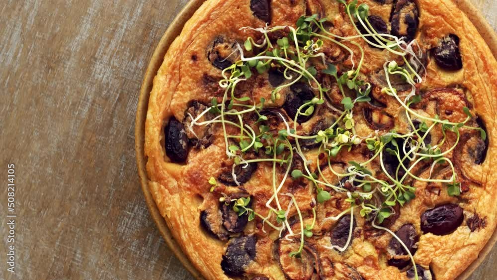 Farinata (Italian chickpea pancake) with kalamata olives with fresh cress sprouts. Homemade dish top view, table spin.